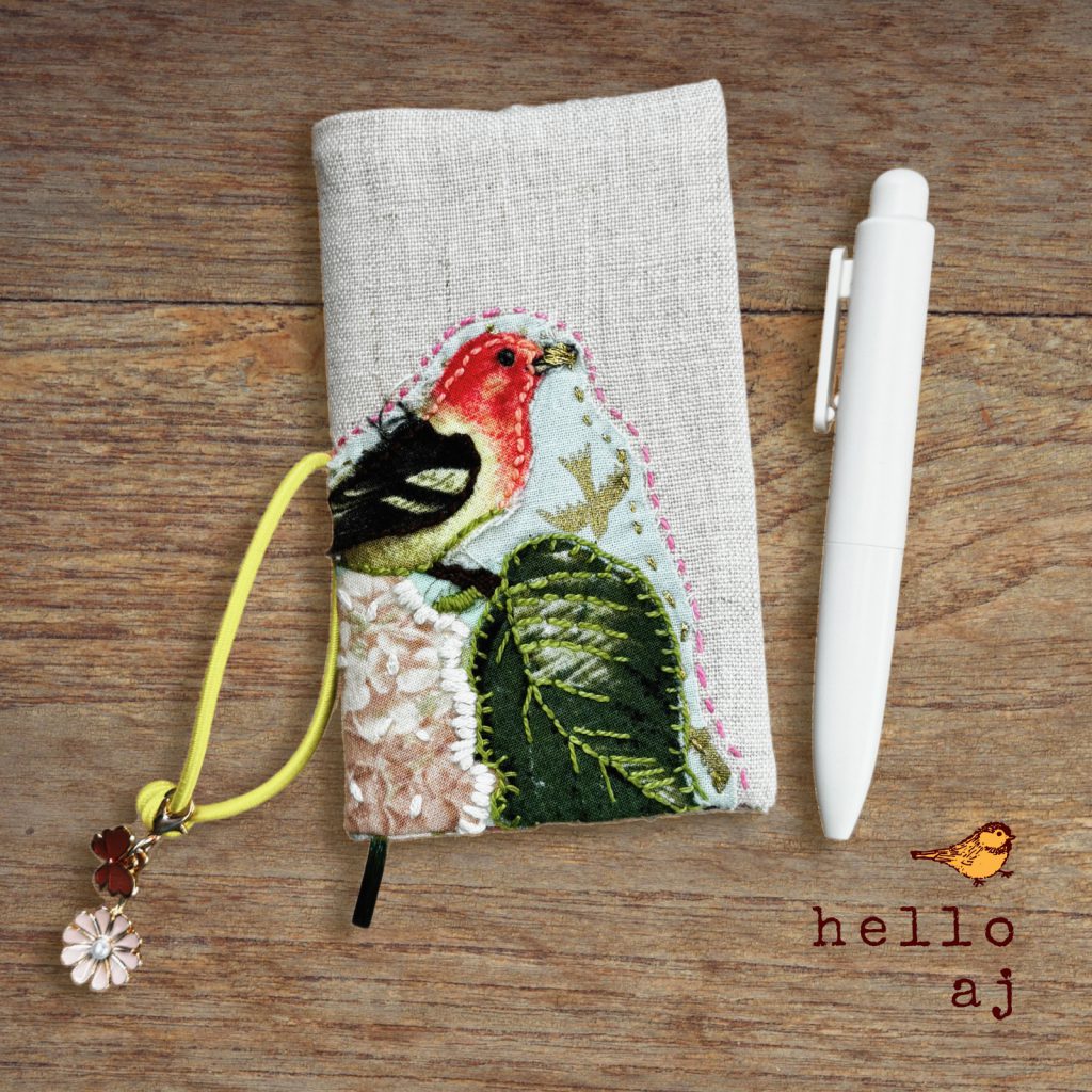 handmade linen journal cover with raw edge applique bird design, shown on journal with elastic closure – hello.aj
