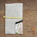 handmade linen journal cover closed back view with elastic strap and floral raw edge applique detail – hello.aj